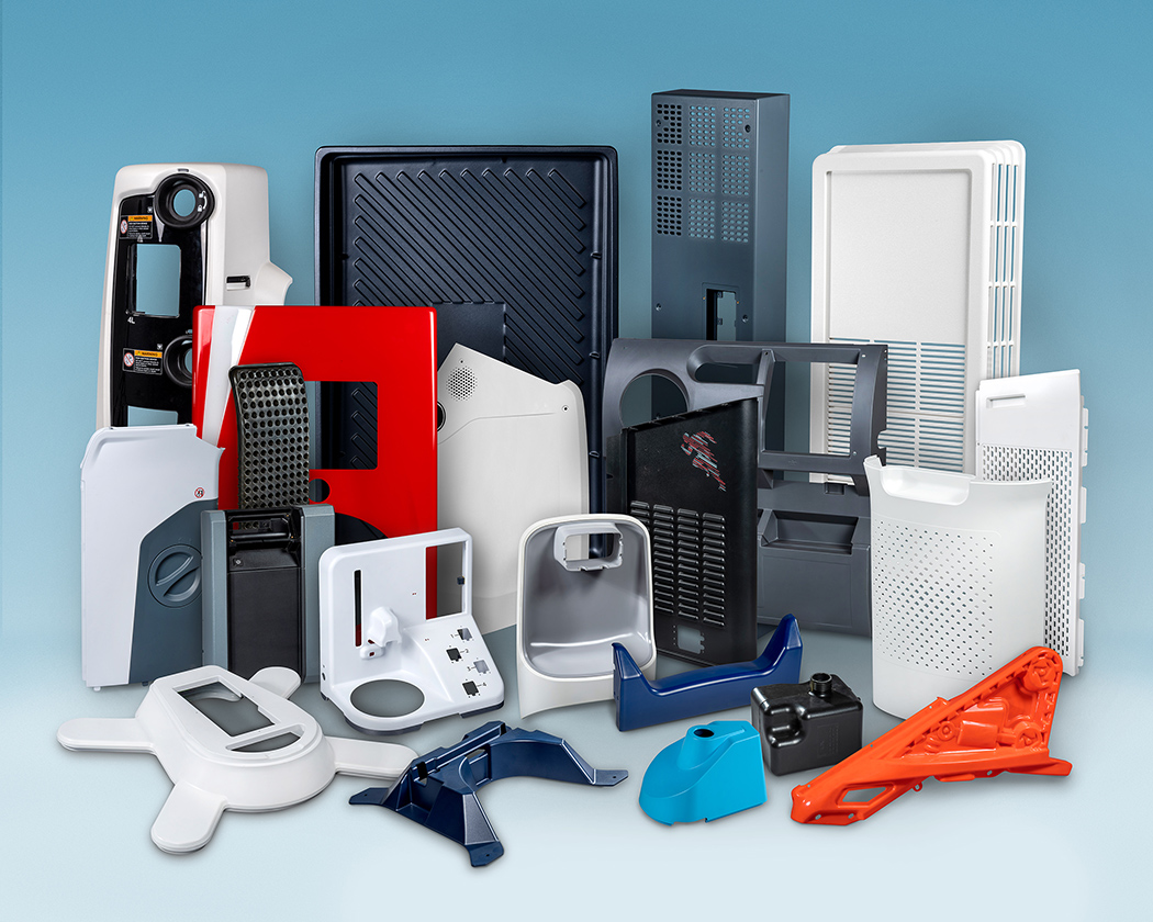 Assortment of molded plastic product parts and device housings arranged against a blue background. The group includes products showing a variety of thermoforming techniques, large rectangular panels, vented covers, and several smaller brackets and casings.